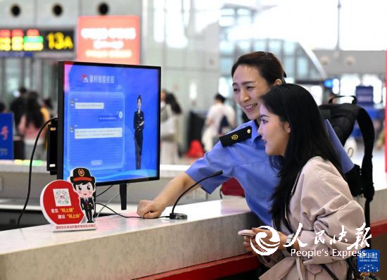 10月5日，在河北石家庄火车站候车大厅服务台，旅客向“AI智能客服机”问询旅行信息。     新华社发（陈其保摄）