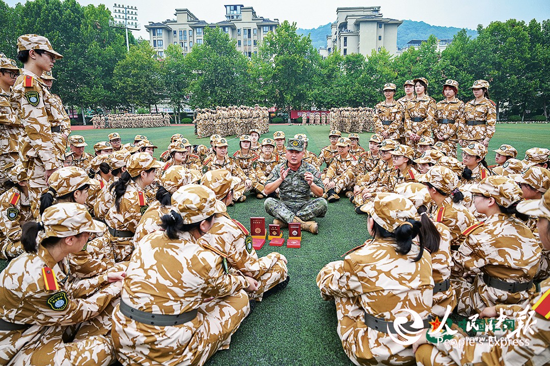 武警重庆总队机动支队为驻地高校开展军训时,穿插组织国防教育活动。图为一级上士安俊吉为学生们讲述所获奖章、纪念章背后的故事。本报特约通讯员 王 肸摄